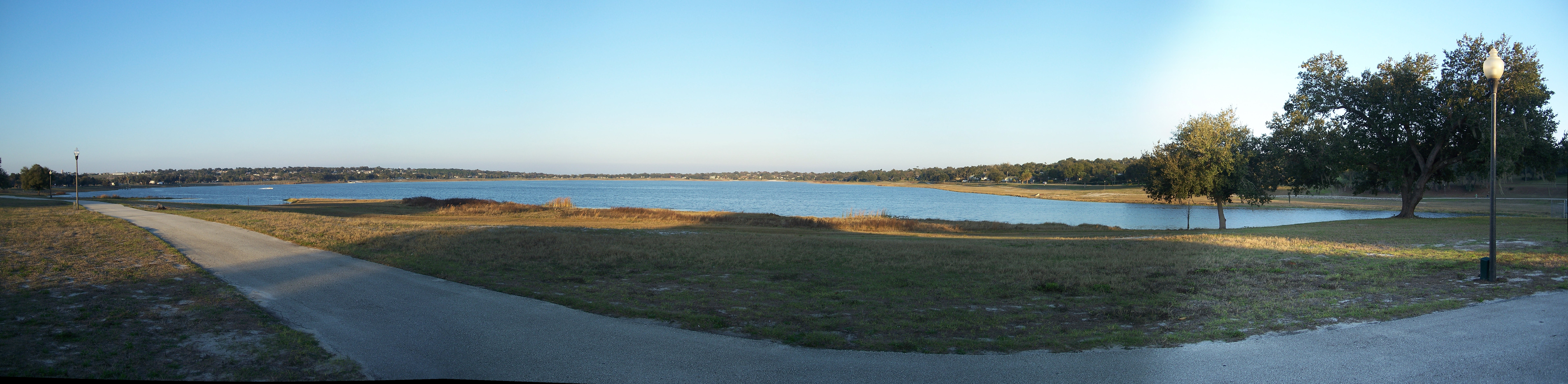 Panoramic view of Lake Wailes and its grassy shoreline beneath a blue sky
